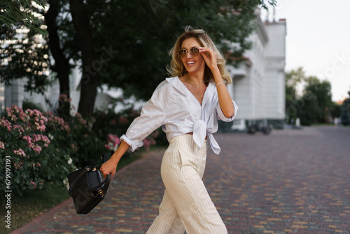 Beautiful blond woman  in stylish fashion casual outfit posing  on the street.  Warm sunset color. photo