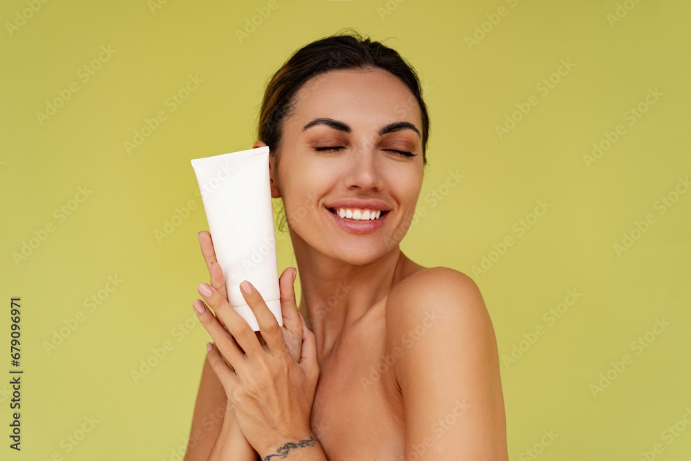 Smiling woman holds tube with cosmetic cream. Photo of attractive woman with perfect makeup on yellow background. Beauty concept Smiling woman holds tube with cosmetic cream. Photo of attractive woman with perfect makeup on yellow background. Beauty concept