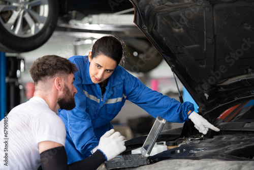 Professional auto mechanic man and woman working together in auto repair shop.