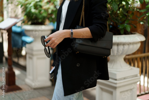 Attractive blond woman in stylish casual outfit posing outdoor. Black jacket, jeans skirt. Fashion details.