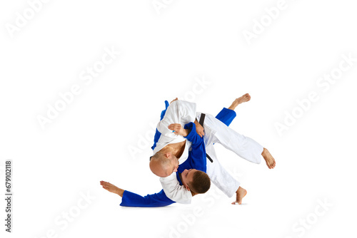 Two male professional sportsmen during match. Karate fighter attacking his opponent with leg technique isolated white background. photo