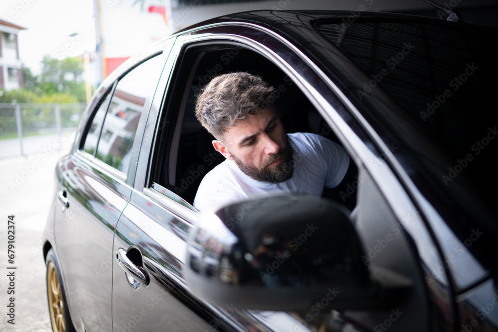 A young man vehicle technician working inside a car at an auto repair shop.