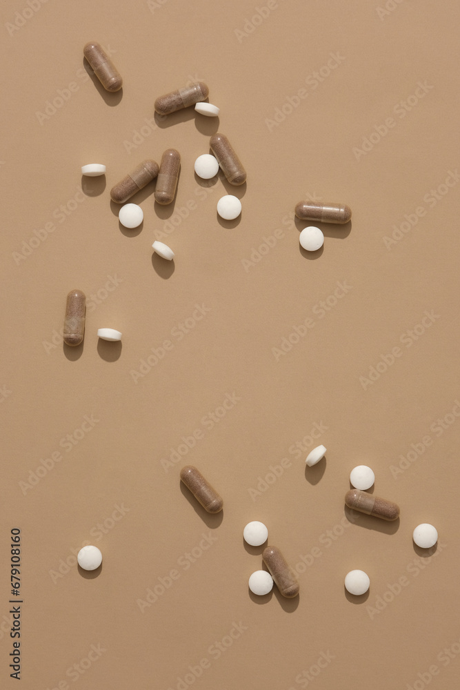Round white pills along with brown capsules are displayed on a pastel brown background. Free space for display and design. Copy space for drug advertising. Round white pills along with brown capsules are displayed on a pastel brown background. Free space for display and design. Copy space for drug advertising.