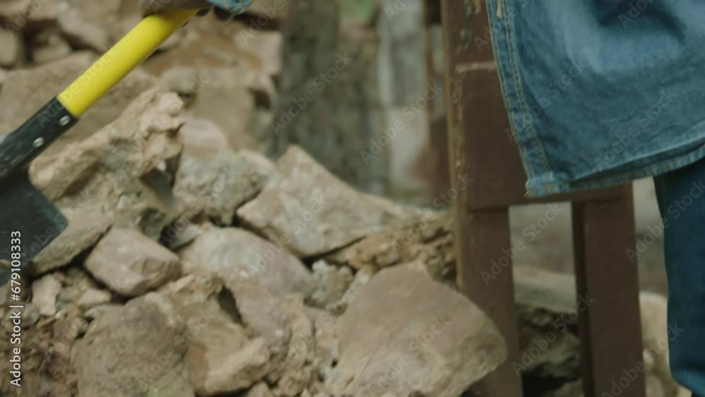 Mature man in hat using shovel while searching for equipment for repairing among stones outdoors Mature man in hat using shovel while searching for equipment for repairing among stones outdoors