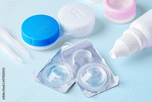 Contact lenses closeup with solution bottle and cases on blue background