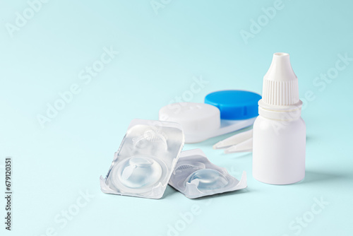 Contact lenses with eye drops and accessories on blue background
