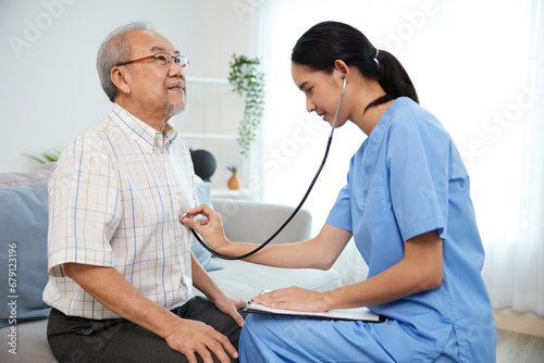 nurse or caregiver using stethoscope to examine senior man at home