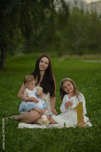 With the softness of the evening light enveloping them, a mother and her children share a quiet moment of affection, highlighting the universal theme of familial love and togetherness.