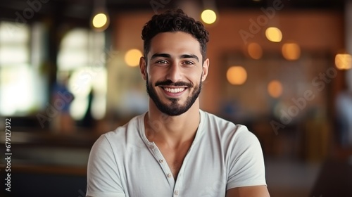 A handsome, bearded young Arab man wearing a plaid turban stood with his arms crossed and smiling. photo