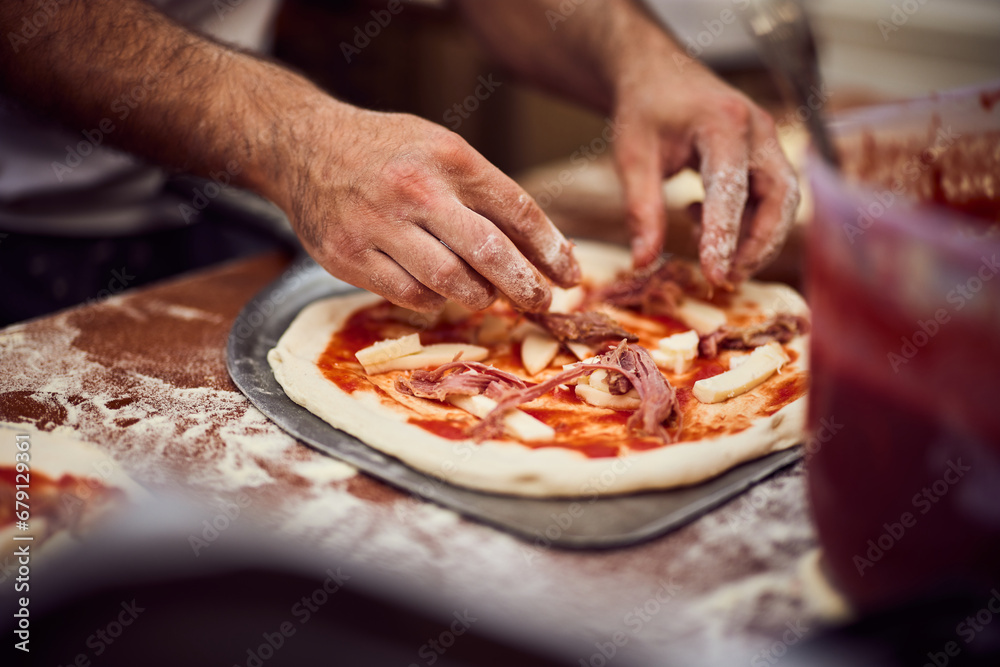 Man making delicious pizza Napoletana, putting a cheese on the top.