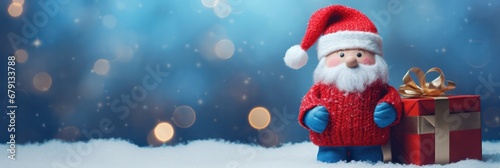 Cute Toy Santa Claus holding a gift box standing in front of the Merry Christmas lighting background with lighting decoration, blur background 2024 © IlluGrapix
