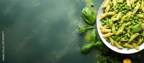 Italian food featuring penne pasta pesto sauce zucchini green peas and basil photographed from above in a flat lay style Copy space image Place for adding text or design photo