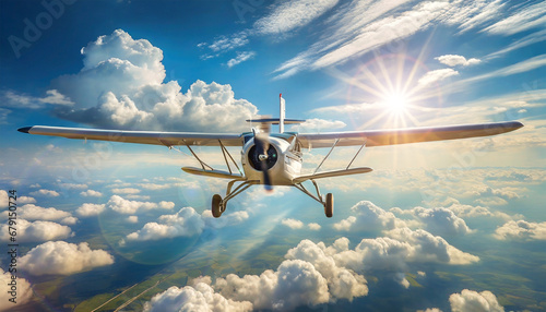 Front view of a small private propeller airplane flying in the clouds, backlit with sunbeams in the background. Aerial view of a plain with green cultivated fields among the white clouds. photo