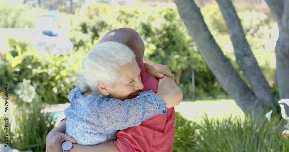 Happy senior biracial couple embracing in sunny garden at home, slow motion Happy senior biracial couple embracing in sunny garden at home, slow motion