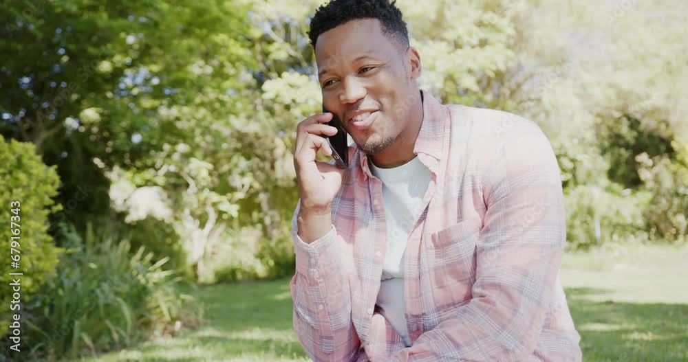 Happy african american man talking on smartphone in garden at home, slow motion Happy african american man talking on smartphone in garden at home, slow motion