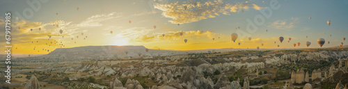 A vast number of hot air balloons in Cappadocia, with the sun about to rise behind the mountains. Golden clouds create a breathtaking panorama. photo