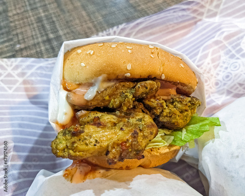 Chicken burger with roasted chicken pieces, ketchup, cheese, and mayonnaise, yummy sauces look very tasty