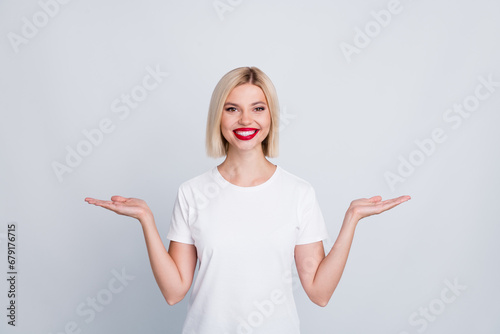 Photo of pretty adorable nice girl wear stylish clothes two arms demonstrate empty space product isolated on grey color background