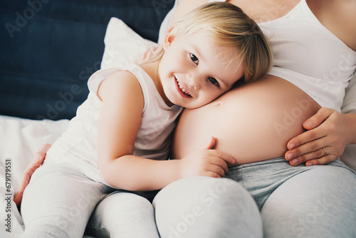 Pregnant mother and daughter resting in bed. Young woman with her first child during second pregnancy. Motherhood and parenting concept.