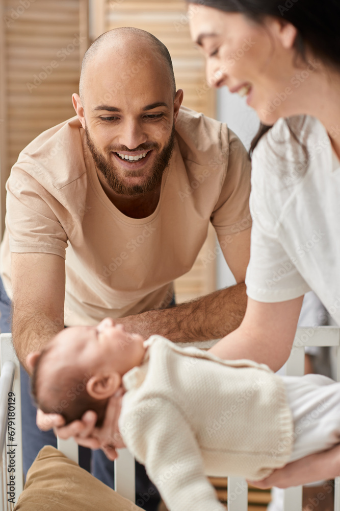 vertical focused shot of bearded happy father looking at his blurred wife holding their newborn baby vertical focused shot of bearded happy father looking at his blurred wife holding their newborn baby