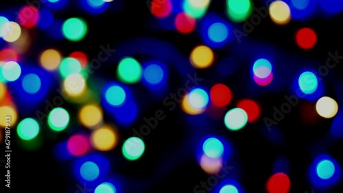 Footage defocused blurry panning motion of multicolored blinker lights bokeh of Christmas and New year decoration lights, abstract, dark background, overlay for party, shallow DOF