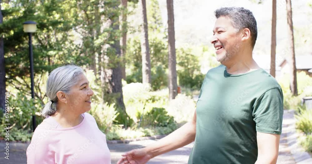 Happy biracial senior couple embracing in sunny garden Happy biracial senior couple embracing in sunny garden