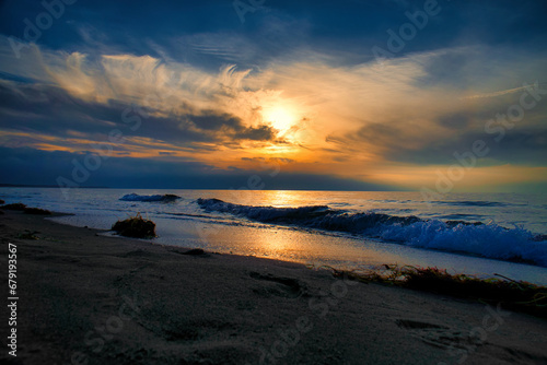 Sunset on the west beach on the Baltic Sea. Waves, beach, cloudy sky and sunshine