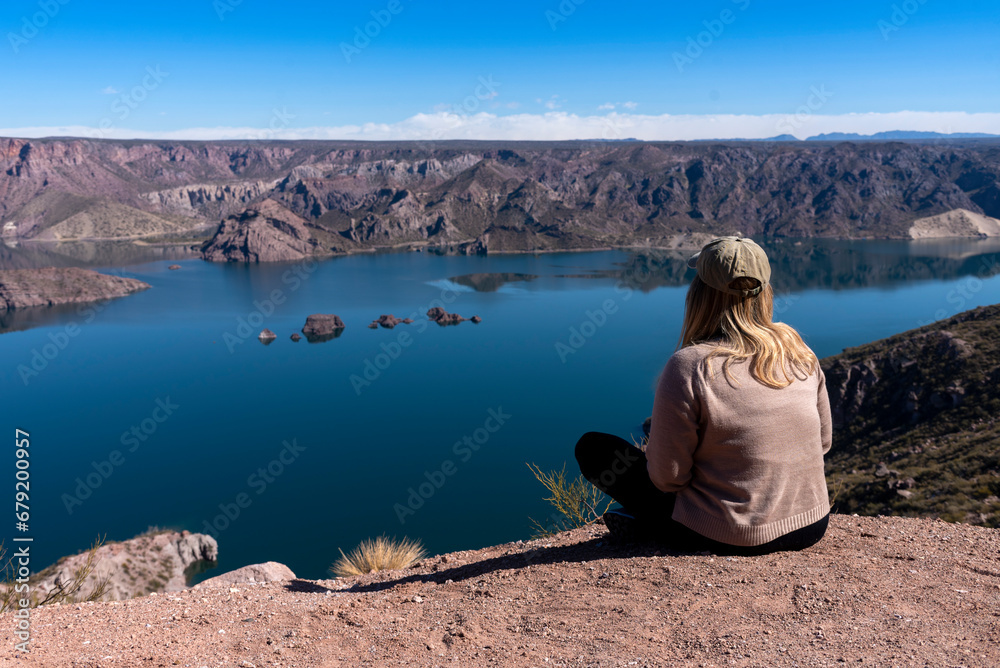young woman with open arms in a landscape of mountains and free lake on a clear sunny day