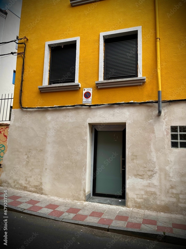 Fototapeta premium Yellow building with two windows and a door