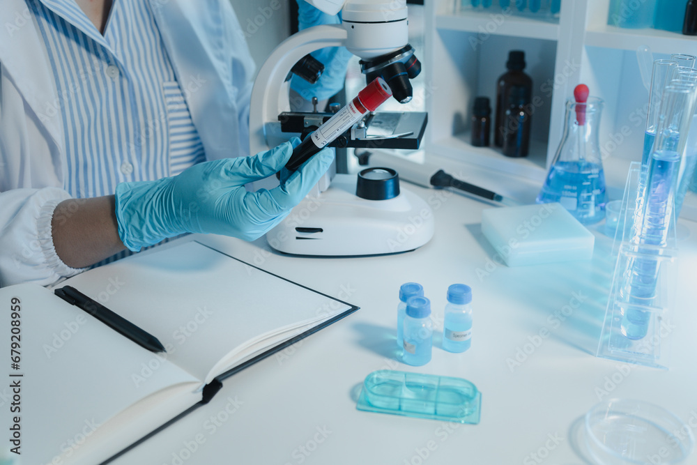 Fototapeta premium A chemist is using a microscope to search for chemicals from blood, Scientist is experimenting with chemicals in the laboratory, Chemist is separating compounds in test tubes with chemical reagents,