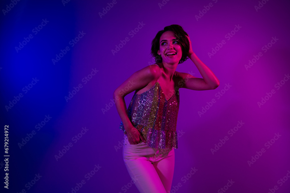 Photo of positive pretty girl have friday night fun in nightclub look empty space isolated bright neon color background Photo of positive pretty girl have friday night fun in nightclub look empty space isolated bright neon color background