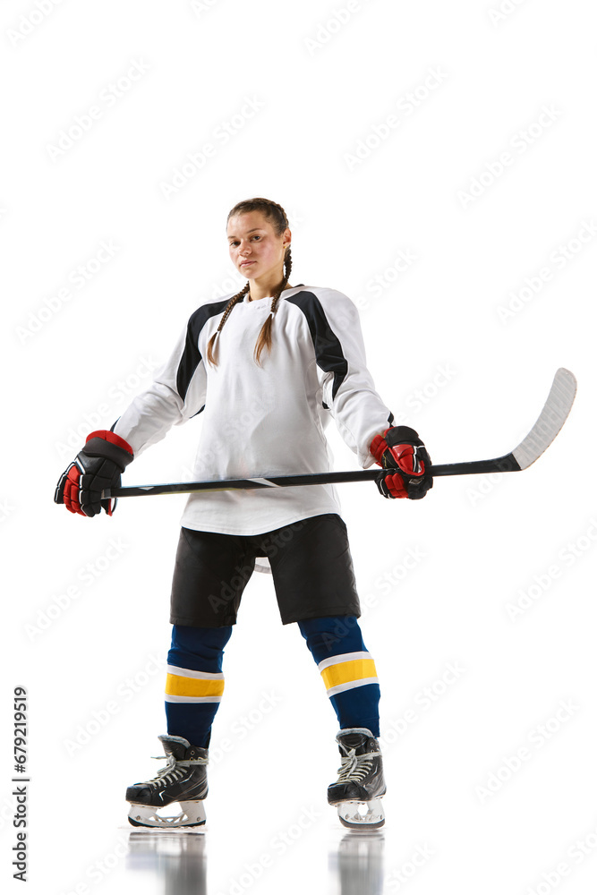 Young girl, hockey player in uniform standing with stick and posing isolated over white background. Champion. Concept of professional sport, competition, game, action, hobby Young girl, hockey player in uniform standing with stick and posing isolated over white background. Champion. Concept of professional sport, competition, game, action, hobby