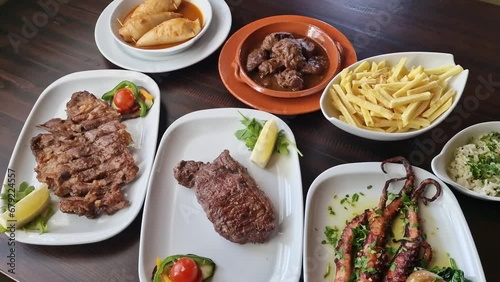 Variety of Portuguese traditional food meat dishes veal pork and octopus with lemon tomato fries, oilive oil rice. photo