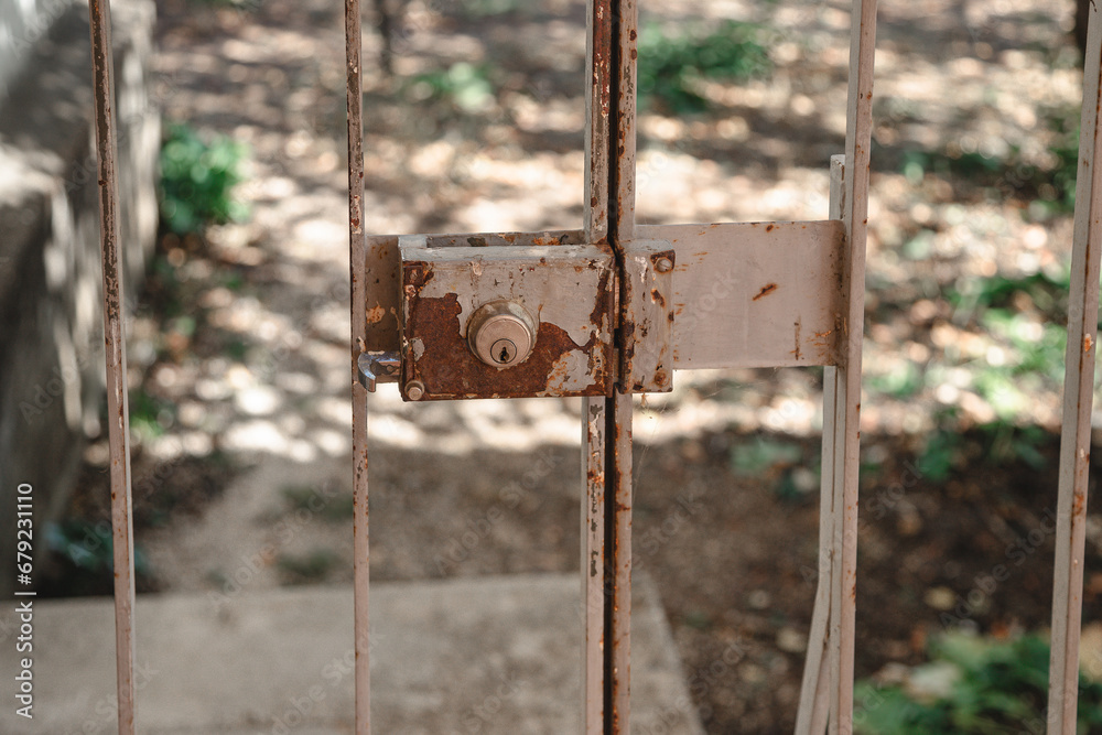 Detail of a lock on the old metal gate with peeling, rusty paint. Detail of a lock on the old metal gate with peeling, rusty paint.