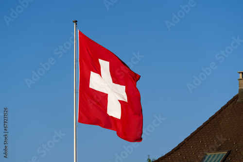 Waving Swiss flag at family home at City of Lenzburg on a sunny evening. Photo taken June 11th, 2023, Lenzburg, Switzerland.