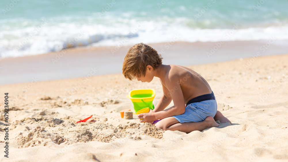 Happy child little boy playing with the sand on the beach, building sand castle, enjoying summer, playing. Advertising for tour operators, hotels, airlines. Vacation concept. Happy child little boy playing with the sand on the beach, building sand castle, enjoying summer, playing. Advertising for tour operators, hotels, airlines. Vacation concept.