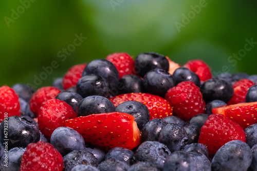 Fototapeta Naklejka Na Ścianę i Meble -  Close-up of juicy blueberries, strawberries, raspberries on a green blurred background. Colorful background of berries, summer food.