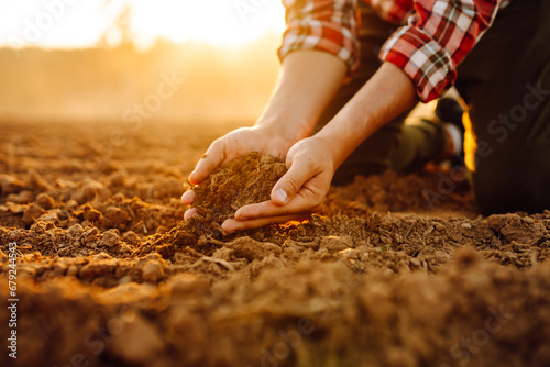 Close-up of a farmer's hands taking black soil from the field. Men's hands move the soil with their hands, checking its quality. Ecology concept.