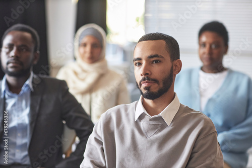Wall Mural Serious multiethnic male immigrant listening to speaker at seminar or conference