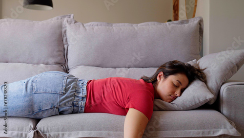 Exhausted or bored young sleepy woman falls down on sofa. Apathetic tired lazy lady sleeping on couch at home alone. Funny girl lying asleep feeling lack of motivation, fatigue or depression concept 