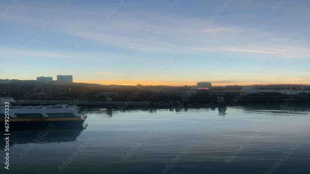 Vertical timelapse of ships in the river in the foreground of a city from day to night
