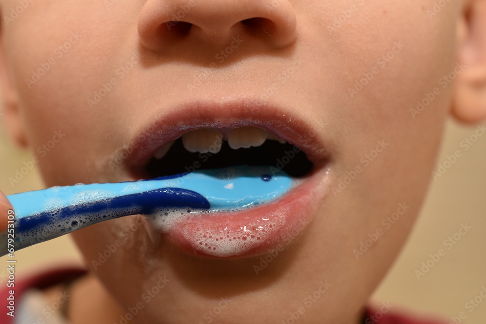 Naklejka premium A boy brushes his teeth with a brush, close-up.