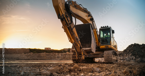 Construction Site On Sunny Evening: Industrial Excavator Driving To Complete Work Tasks Related To Building New Real Estate Project. Man Operating Heavy Machinery To Build New Apartment Complex.