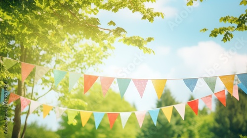 Vibrant blue sky backdrop with lush green tree branches, adorned with strings of small triangle flags, creating a festive summer atmosphere with ample open blue space for text.