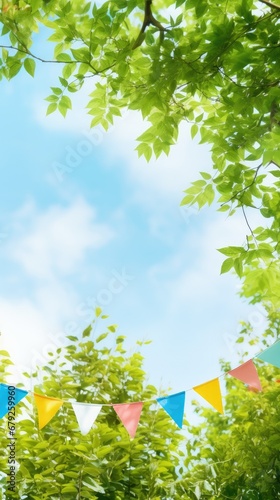 Vibrant blue sky backdrop with lush green tree branches, adorned with strings of small triangle flags, creating a festive summer atmosphere with ample open blue space for text.