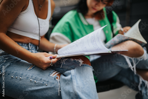 Casually dressed high school girls study outdoors, discussing a school project and preparing for an exam. They enjoy teamwork, sharing knowledge, and the joy of learning.