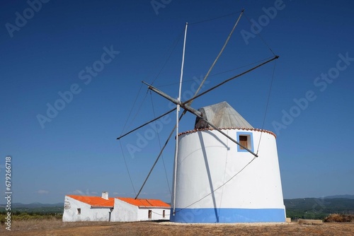 White windmill in a barren dry field against a clear blue sky