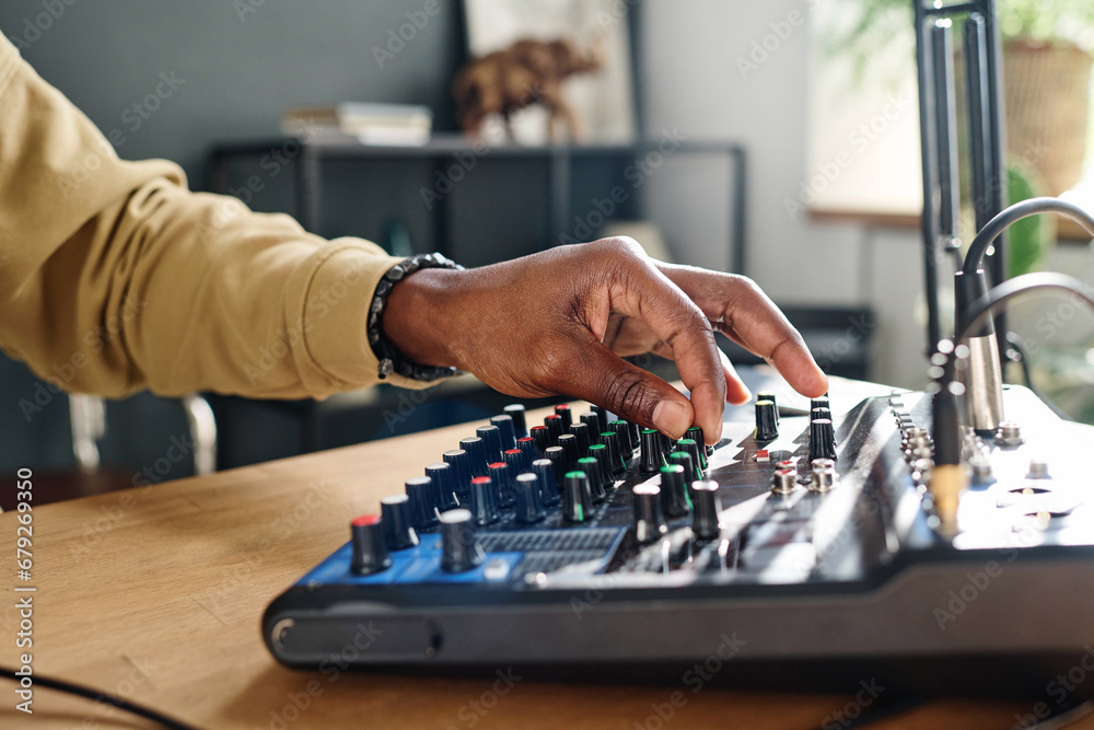 Fototapeta premium Hand of young male host turning consoles on soundboard and adjusting sounds while preparing for recording new podcast or audio