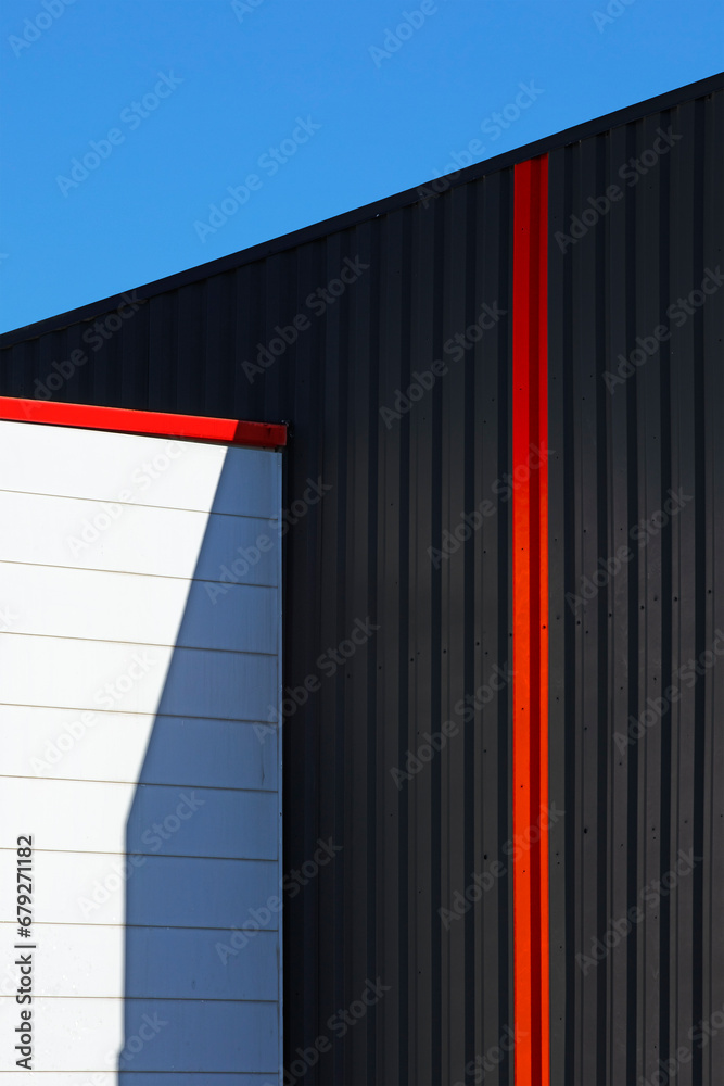 Architecture industrielle noir et couleur en habillage métallique d'un mur de façade de bâtiment moderne dans une zone commerciale. - obrazy, fototapety, plakaty 