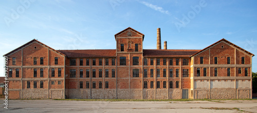 Ancienne usine désaffectée en brique rouge avec ses bâtiments symétriques et ses cheminées en brique du 19e siècle. 